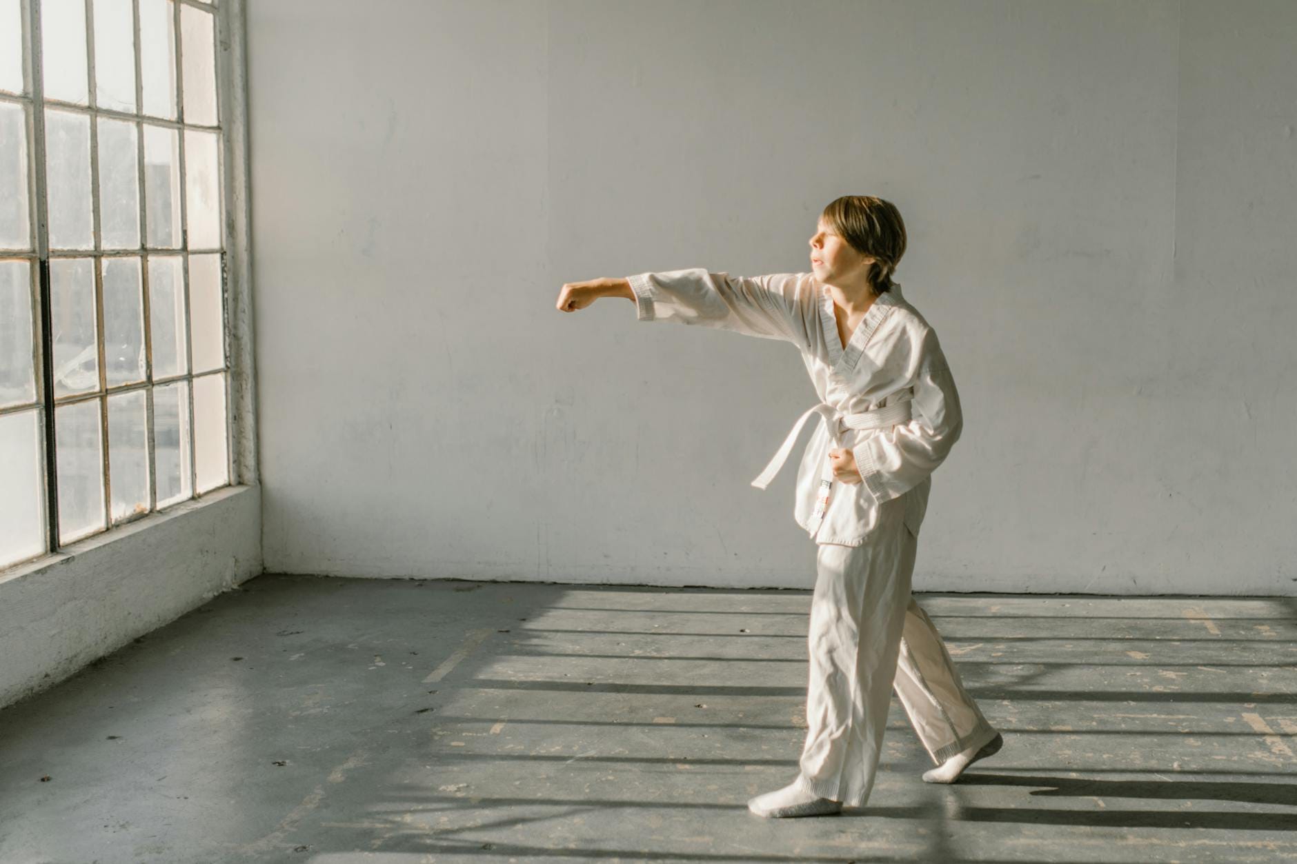 Młody adept sztuk walki w doboku trenuje ciosy na sali