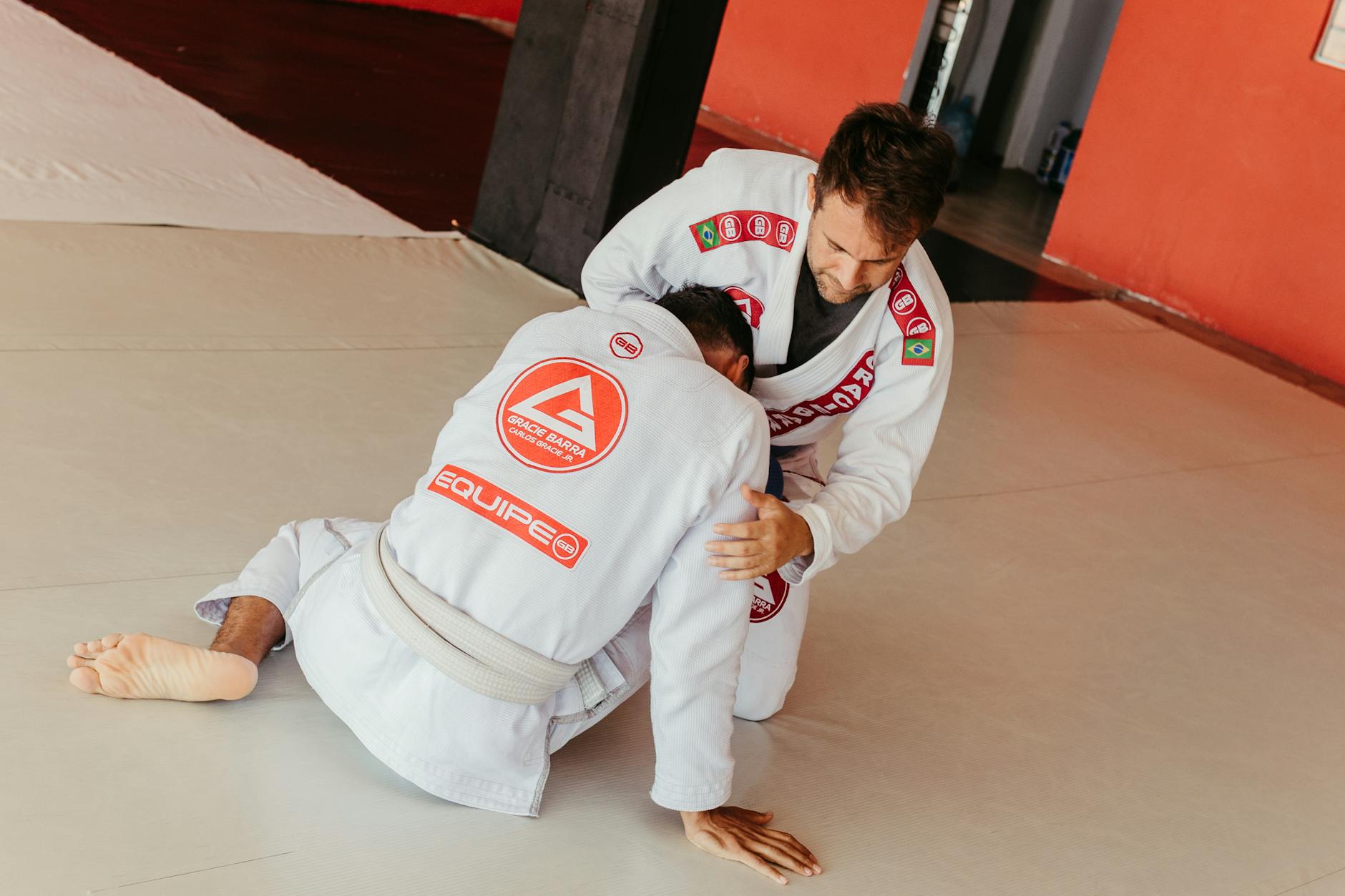 Dwaj zawodnicy BJJ w kimonach ćwiczą przejścia do trzymania w parterze