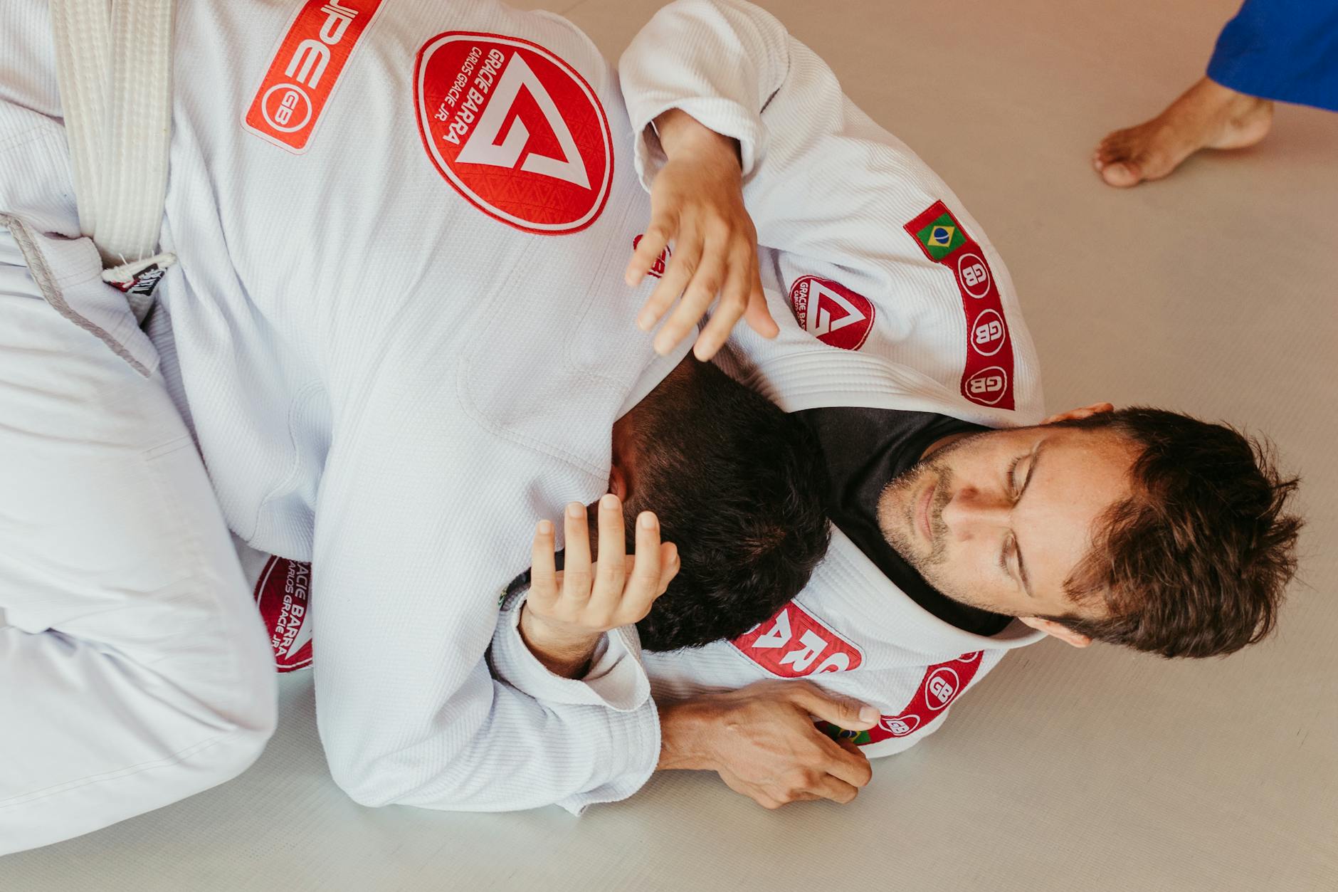 Dwóch mężczyzn w walce BJJ, zawodnik z góry kontroluje przeciwnika
