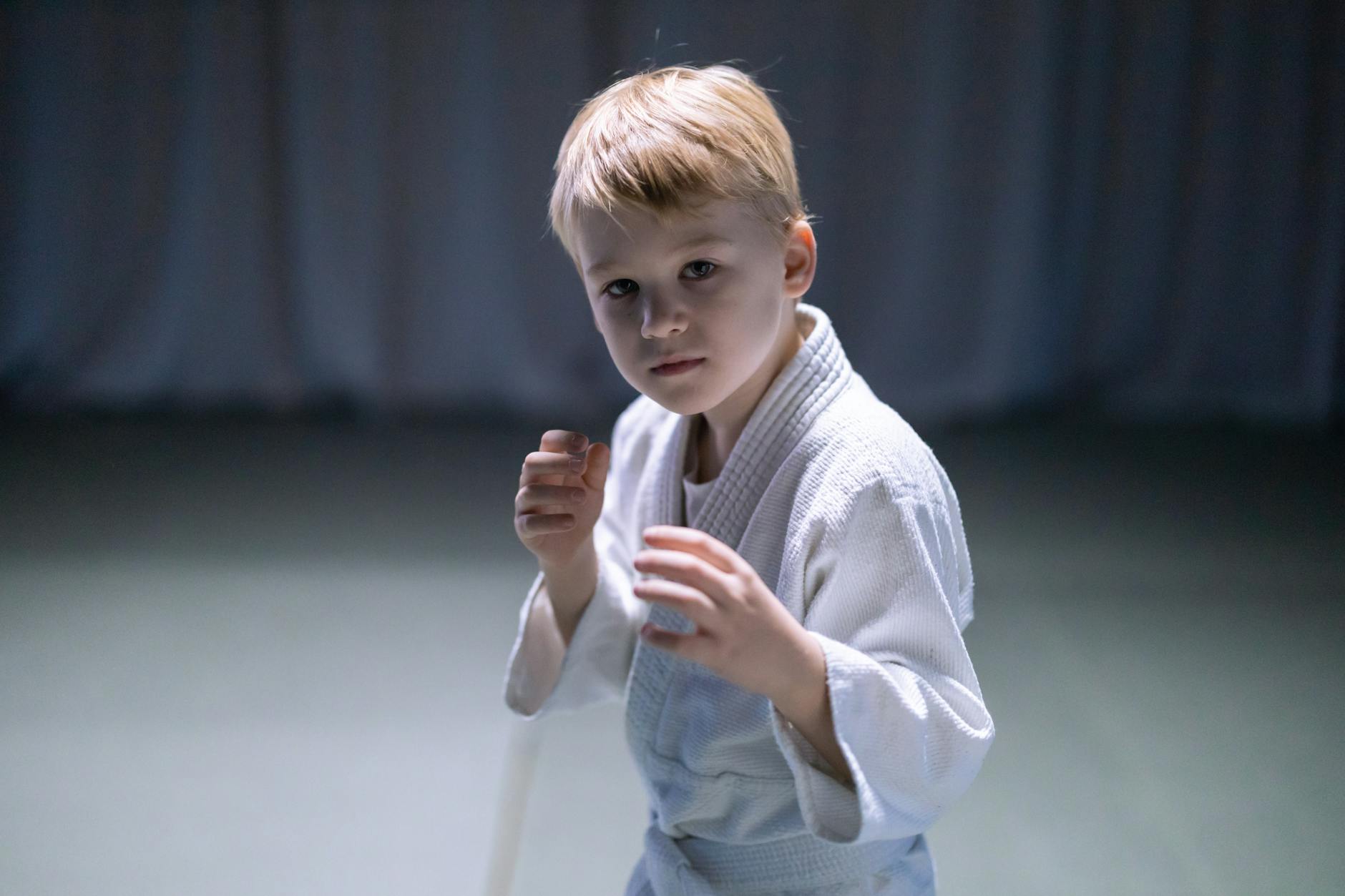 Chłopiec trenujący sztuki walki w sali, skupiony przed randori