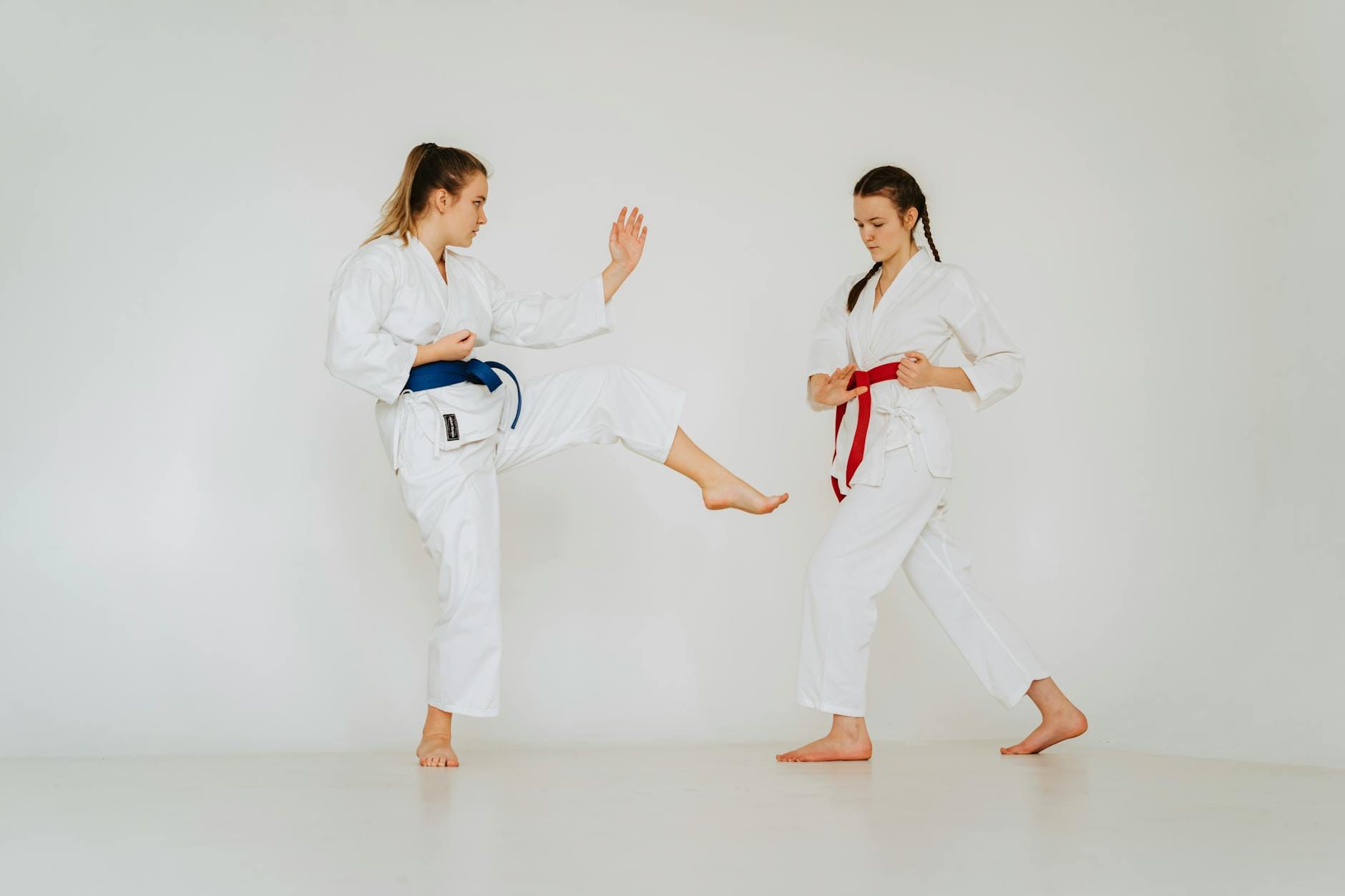 Dwie dziewczynki w kimonach trenują podstawowe techniki karate