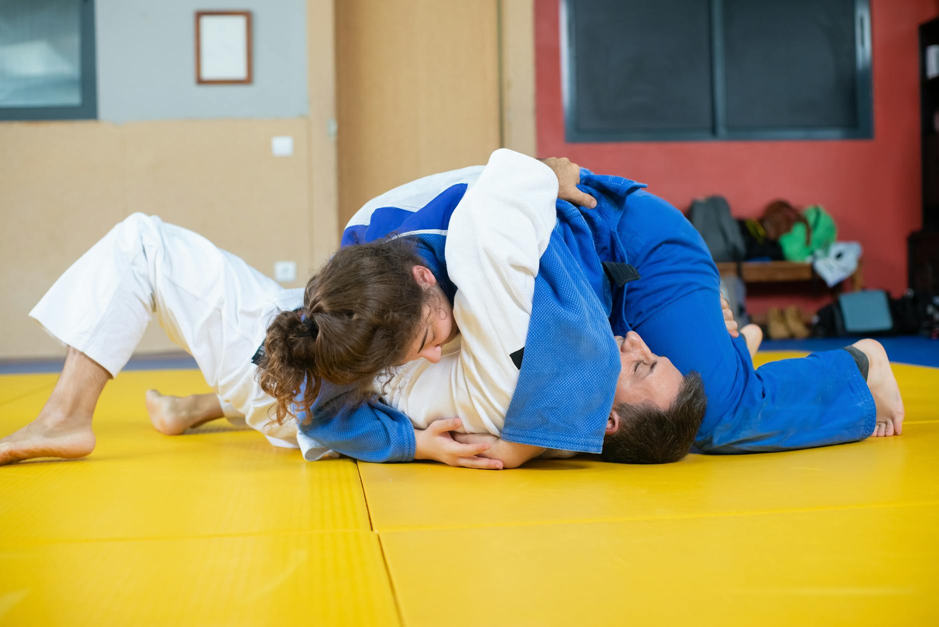 Dwóch judoków ćwiczy techniki trzymania osaekomi w dojo
