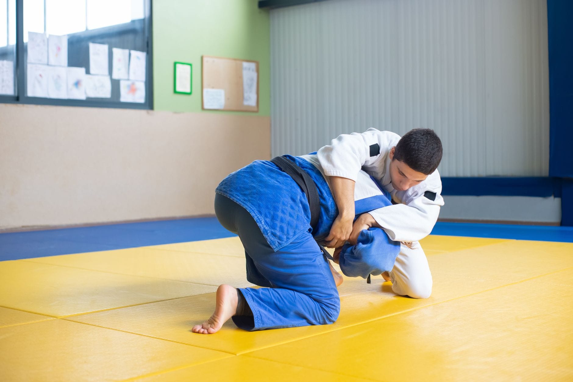 Dwóch judoków trenuje techniki na macie w dojo