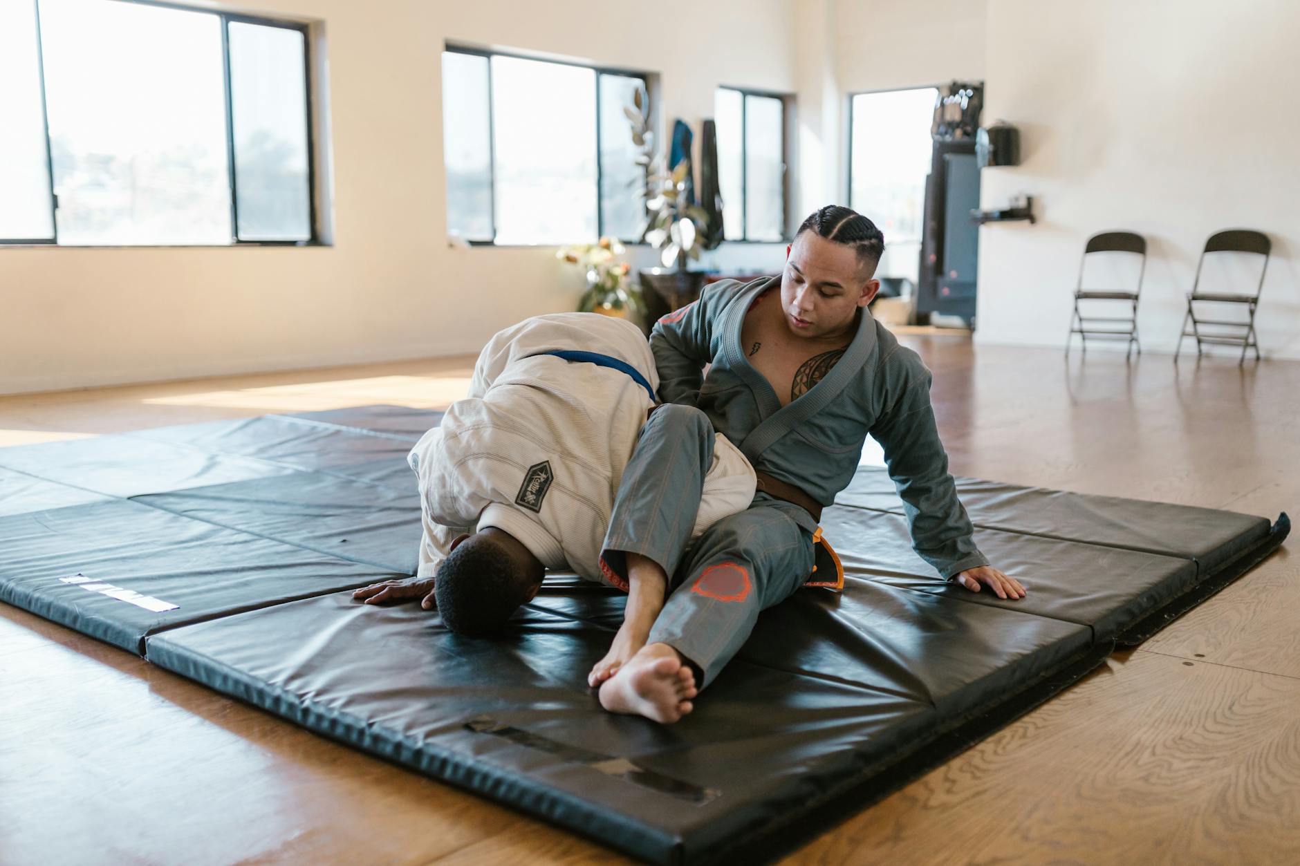 Dwóch zawodników judo trenuje trzymanie w parterze na macie