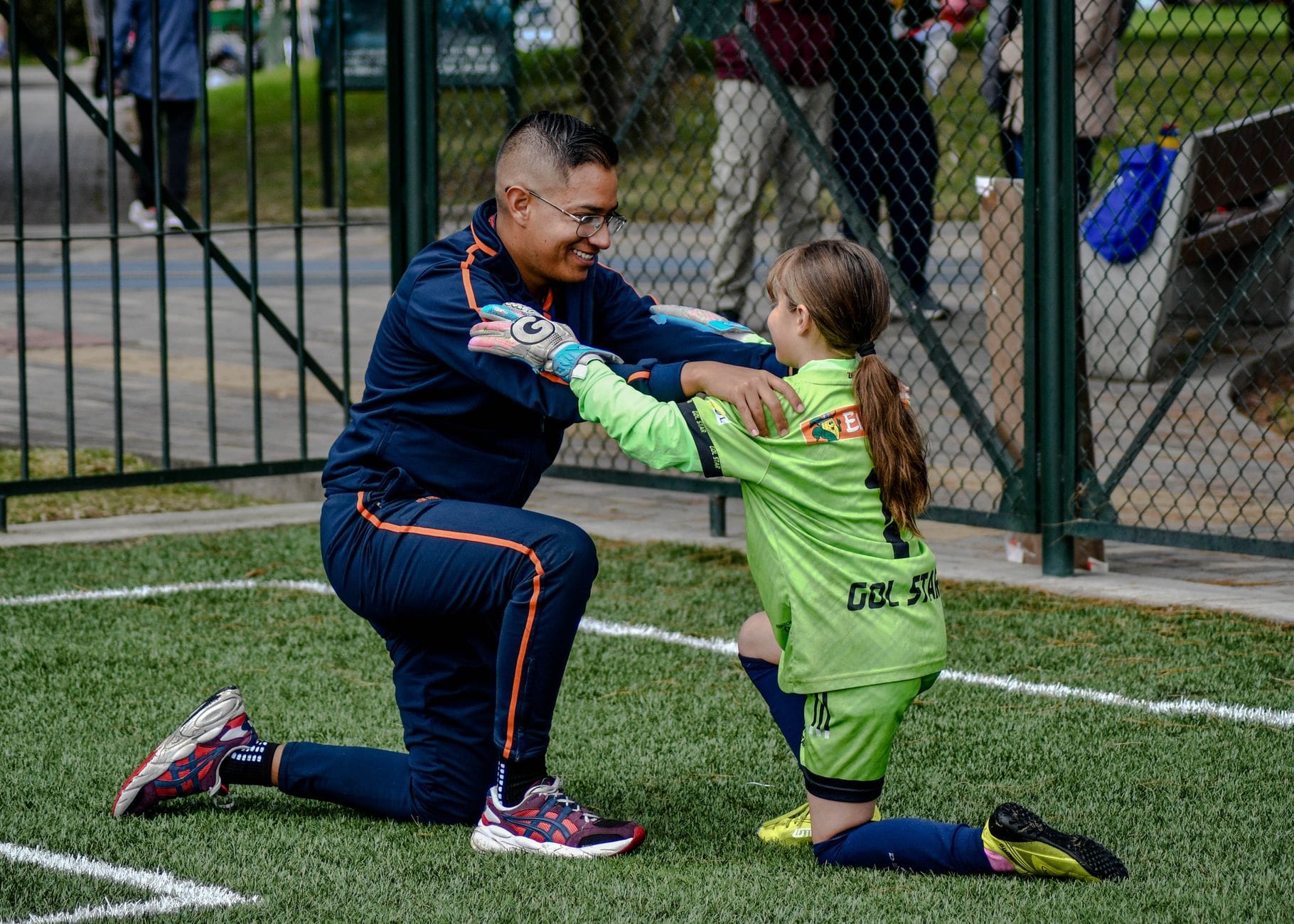 Trener klęczy i wspiera młodą piłkarkę na boisku