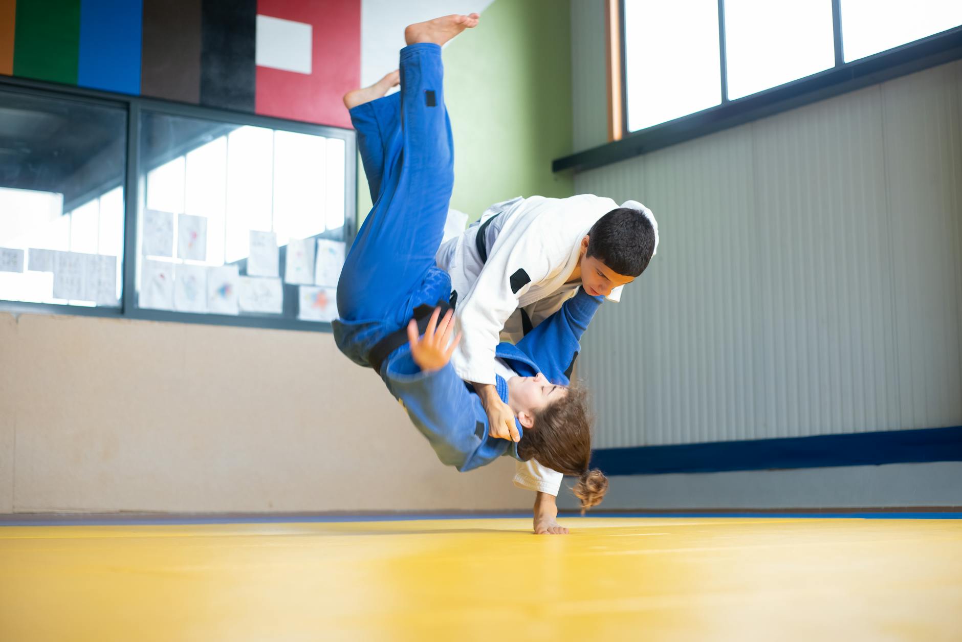 Zawodnicy judo ćwiczą dynamiczny rzut i bezpieczny upadek na macie