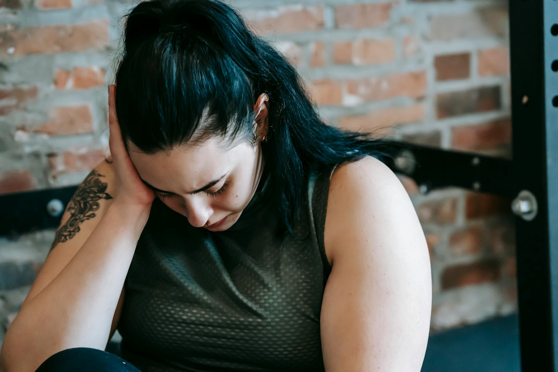 Zrezygnowana kobieta siedzi przy sprzęcie na siłowni podczas treningu