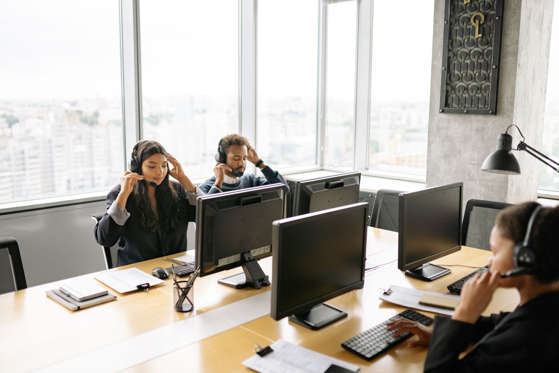 Pracownicy call center przy komputerach w jasnym biurze