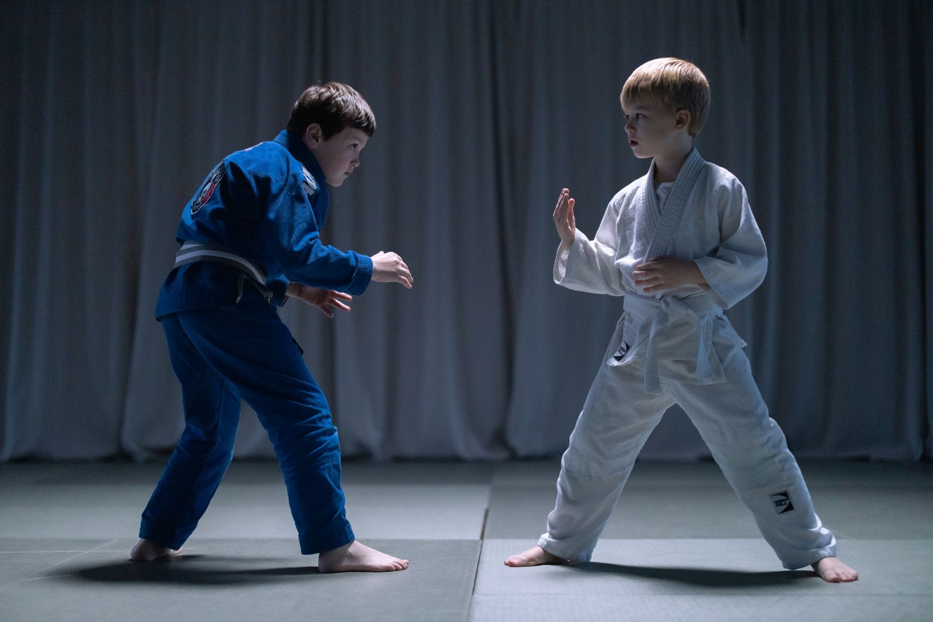 Dwóch chłopców w judogi ćwiczy techniki judo na macie indoors