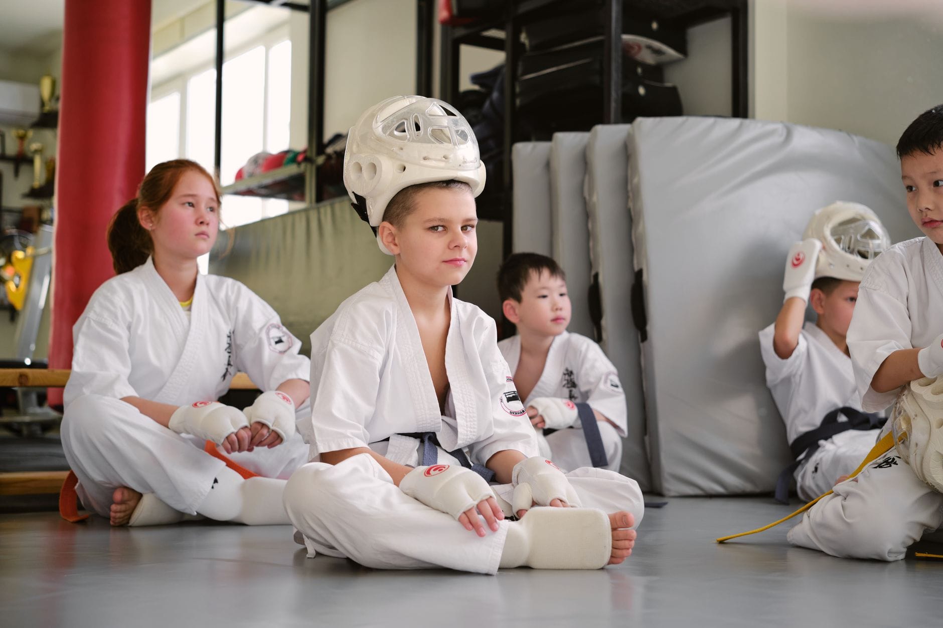 Dzieci w kimonach siedzą w dojo przed treningiem judo