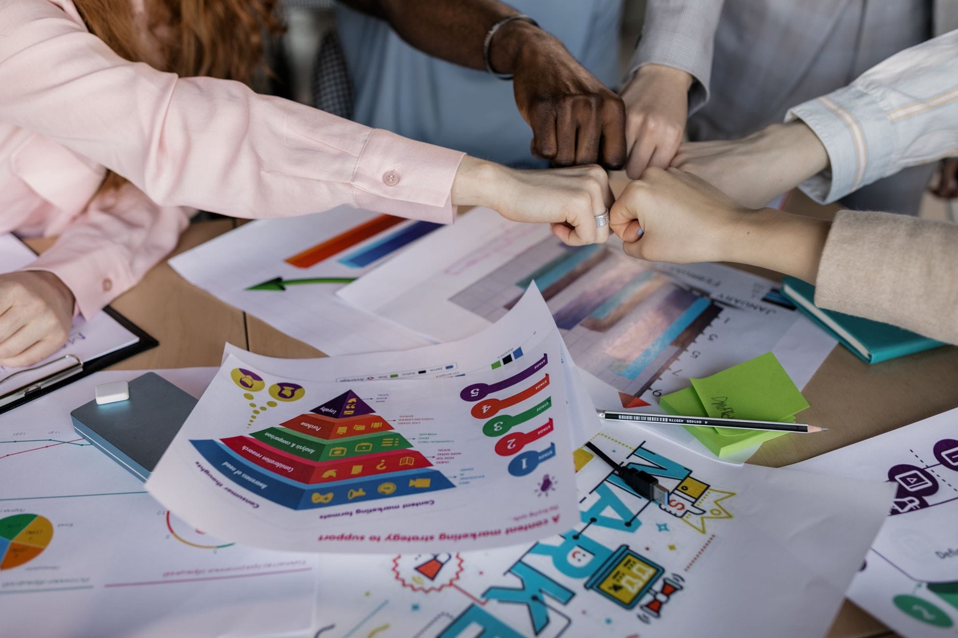 Zespół łączy dłonie nad raportami biznesowymi i strategiami marketingu