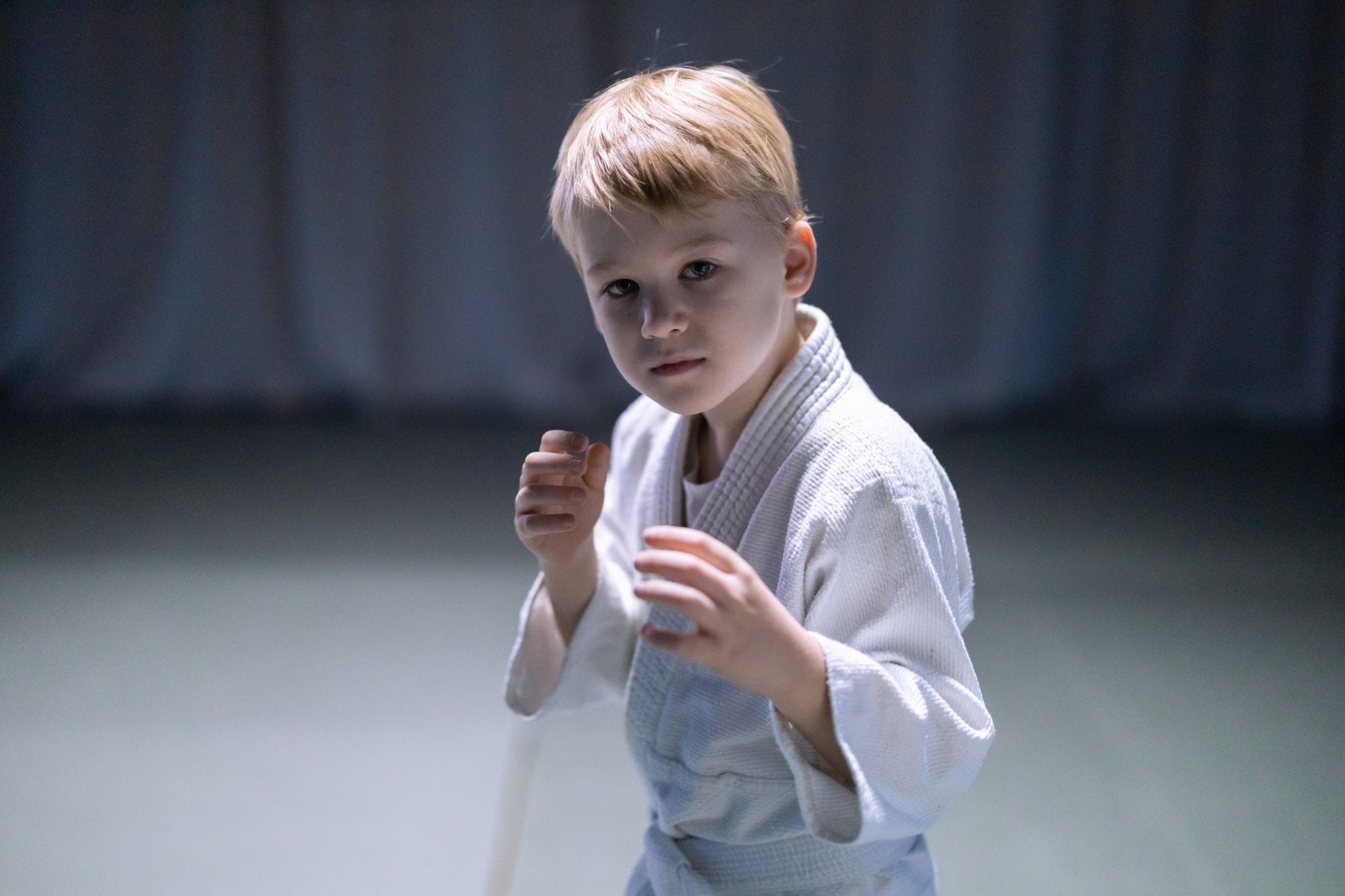 Zajęcia próbne judo: jak poznać, że trener dobrze pracuje z dziećmi Chłopiec w stroju sportowym ćwiczy judo na macie w sali