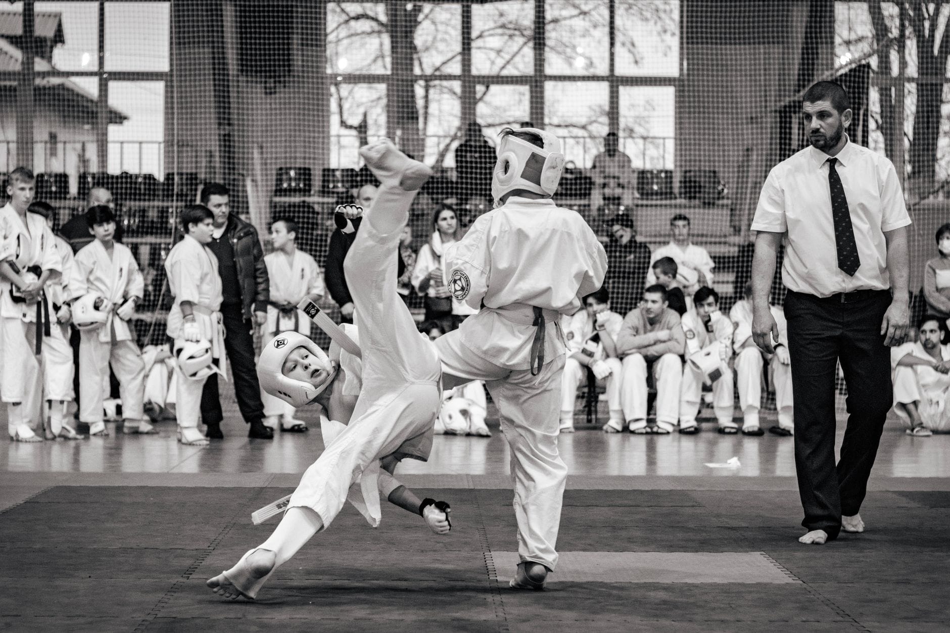 Zawodnicy karate w trakcie walki turniejowej pod okiem sędziego