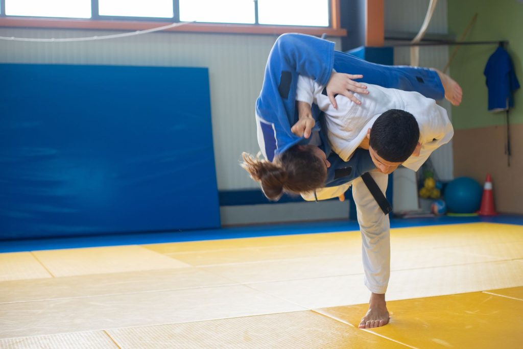 Judocy ćwiczą rzut uchi mata na macie podczas treningu